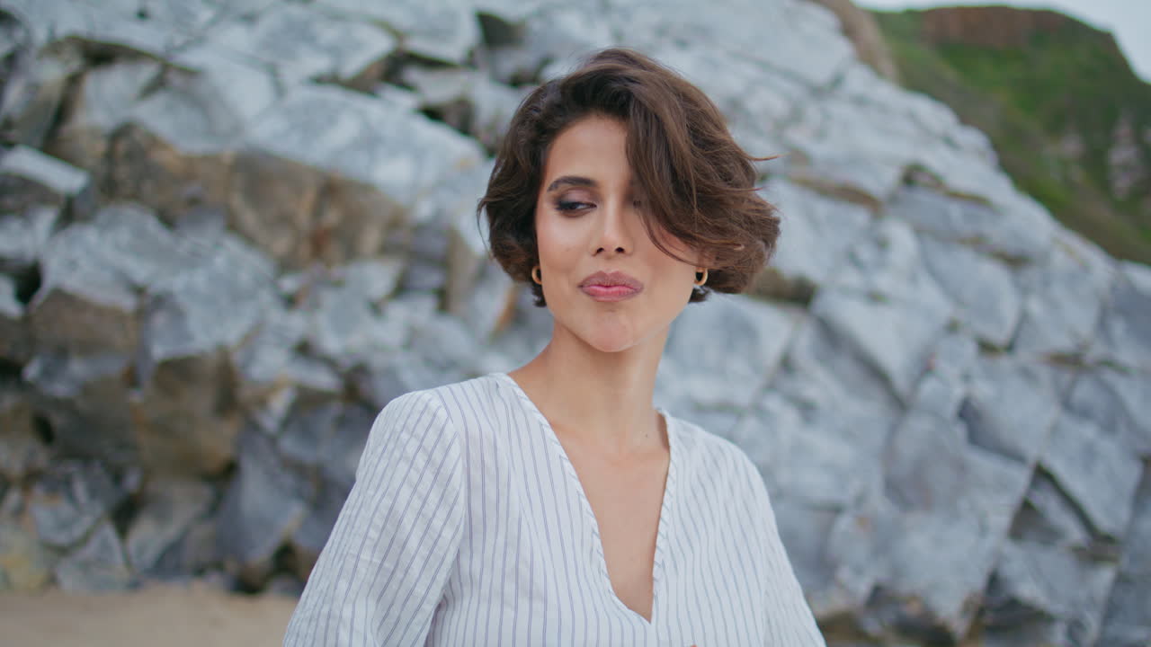 Bella ragazza che mangia un croissant a un picnic in spiaggia. Primo piano di mani che tengono un panino sulla riva.