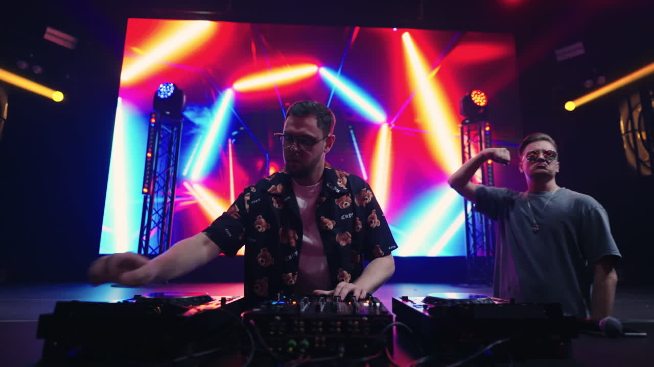 dos djs actuando en el escenario de un club