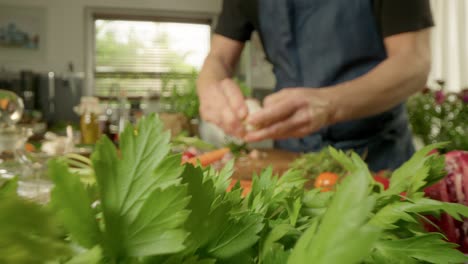 aplastando un bulbo de ajo entre verduras de colores en la tabla de cortar