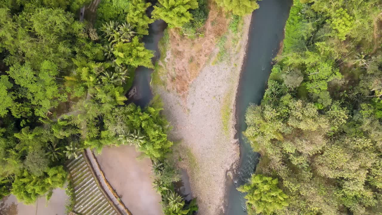 avión no tripulado vuela sobre un río tópico en el campo de indonesia con densos árboles