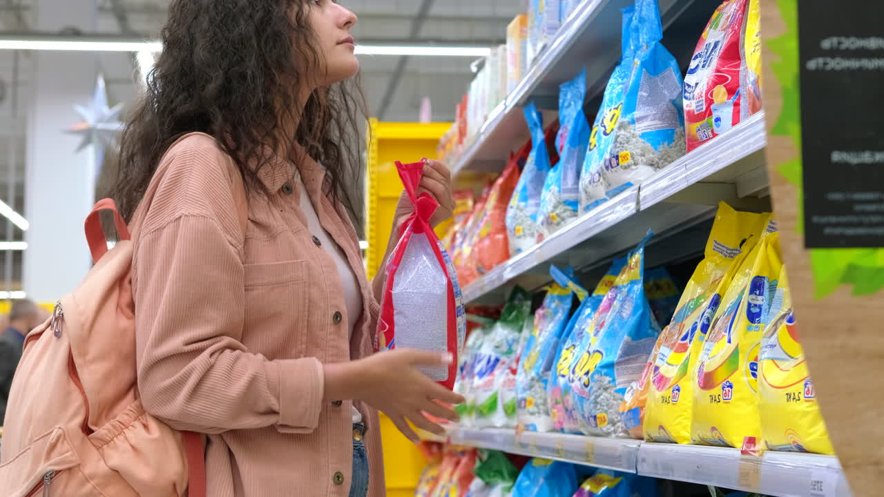 한 여성 이 식료품 가게 에서 세탁 용액 을 구입 하고 있다