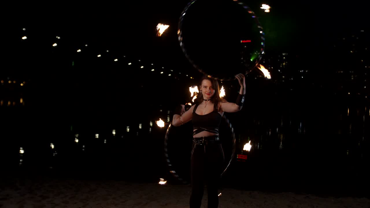 niña de fuego realizando el arte de retorcer aros al anochecer