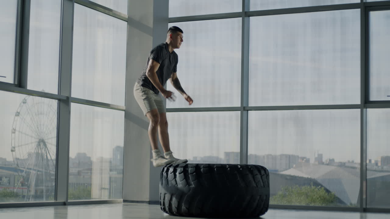 Man Performing Tire Flip Exercise in Gym