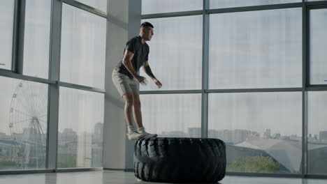 man performing tire flip exercise in gym
