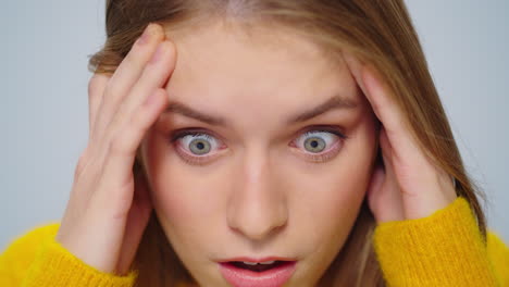 Closeup-exhausted-woman-with-migraine-posing-at-camera-on-grey-background.