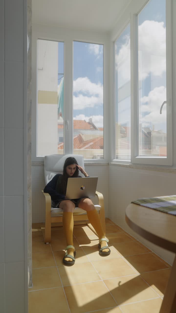Teenager working on a laptop on a balcony