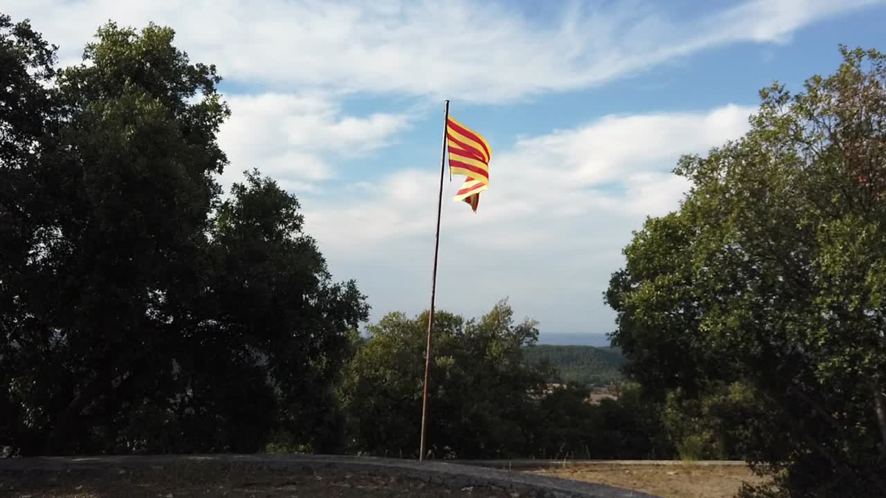acercar la bandera catalana en la cima de una colina, con vistas a las colinas con un cielo nublado