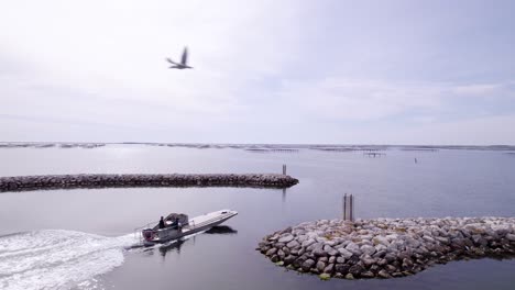 seguimiento aéreo de una lancha a motor que sale de un muelle cerca de una granja de moluscos en sete, francia