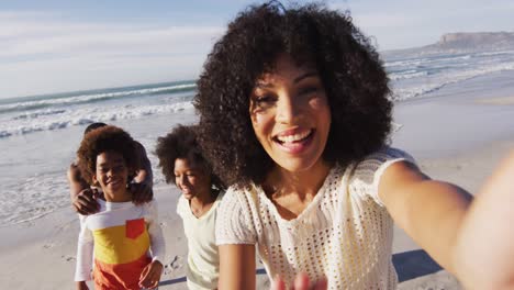 Padres-Afroamericanos-Sonrientes-Y-Sus-Hijos-Tomándose-Un-Selfie-Con-Un-Teléfono-Inteligente-En-La-Playa