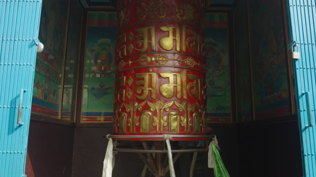 An elderly Buddhist woman rotates the prayer wheel while counting her beads and chanting mantras inside a temple in Nepal. A moment of spirituality, peace, and deep cultural devotion captured