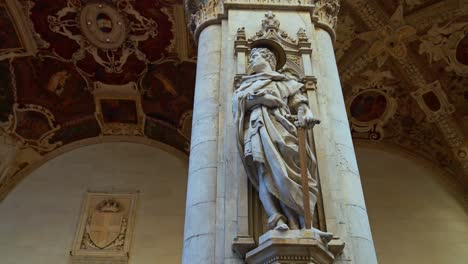 una estatua adorna un pilar de la logia de los comerciantes, loggia della mercanzia ubicada detrás de la plaza del campo, en siena, italia