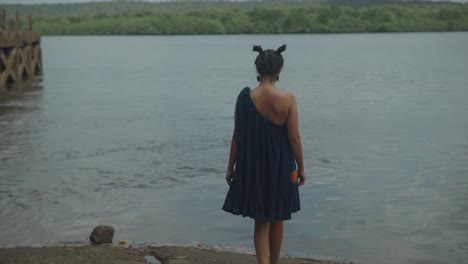 Woman-walking-towards-river-wearing-dark-dress