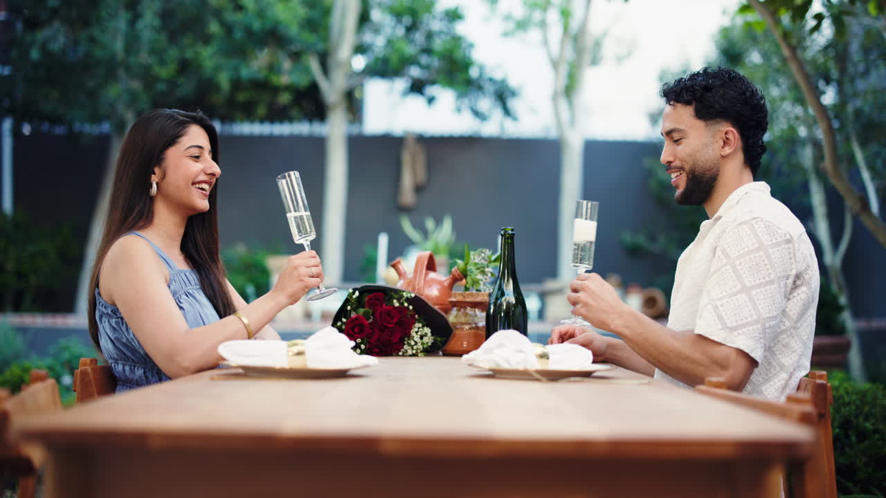 Giovane coppia che brinda romanticamente con champagne in un giardino