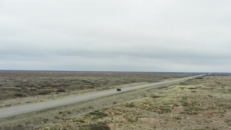 car driving through majestic desert flatlands on asphalt highway