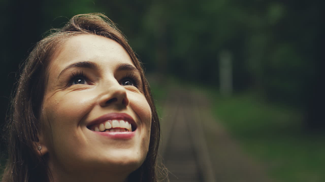 primer plano de una mujer joven y bonita sonriendo mientras disfruta de la lluvia