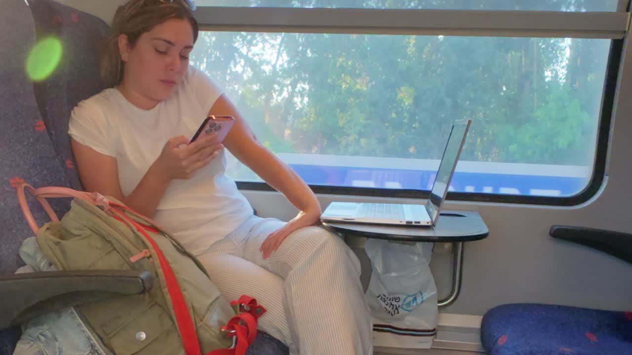 Woman Using Smartphone and Laptop During a Train Commute