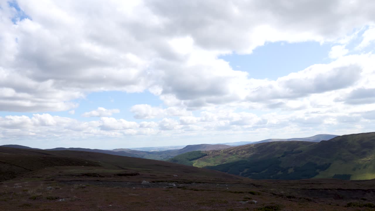 Slow panning shot of Scottish Highlands valley, cloudy sky, heather moorland, natural daylight