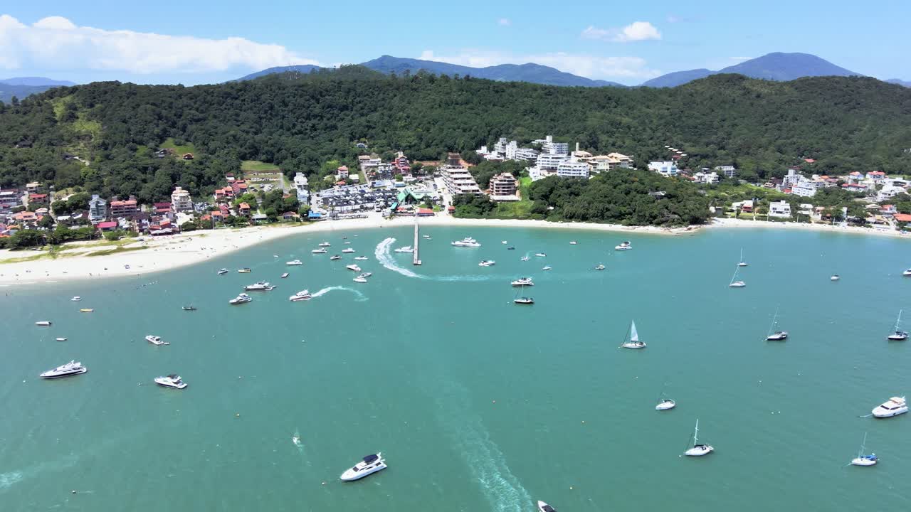 카나주레 해변 플로리아노폴리스 산타 카타리나의 파라디시아카 해변에 부두가 있는 쾌속정 요트와 고급 보트 위로 높이 날아가는 드론의 공중 장면