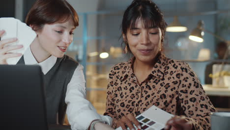 female colleagues discussing color palette at night in office