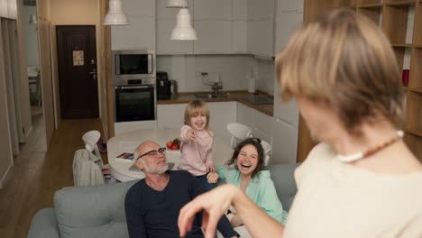 playful crazy young daddy performing parody to guess together with a family in living room interior