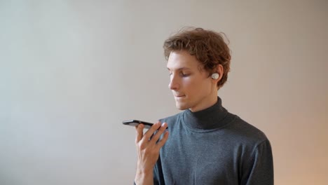 cute-curly-guy-dictates-text-to-smartphone-and-listens-to-translation-in-headphones