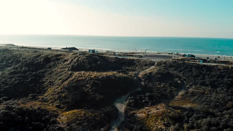 coastal ocean road aerial view panning left to sandy dune terrain