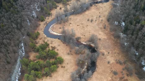 aerial: curvy river flows across forest in early spring in eastern europe
