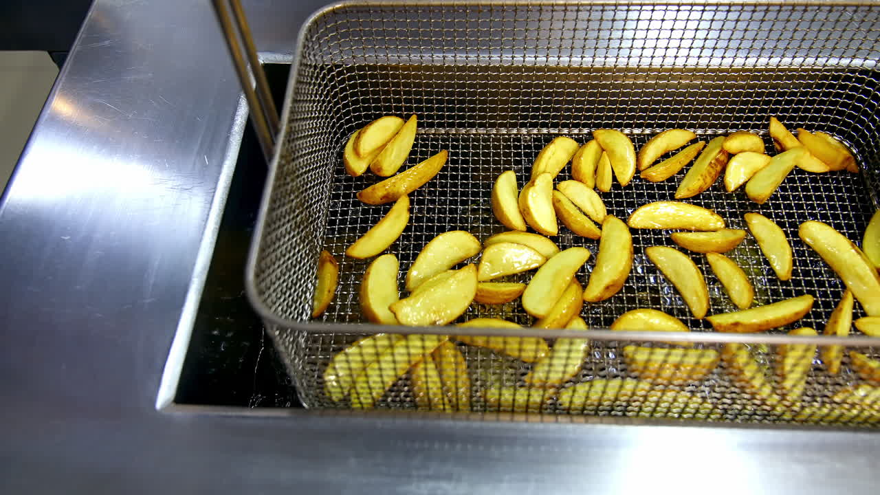 French fries cooking. Grid with strips of potato lowered into boiling oil. The concept of fast food, delicious unhealthy food.