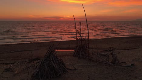 playa de arena durante la puesta del sol con tipis de madera a la deriva