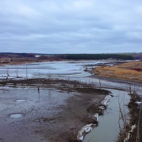 Water pollution. Narrow river floating among dirty background of nature in spring