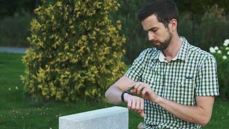 hombre comprobando el reloj inteligente en un parque