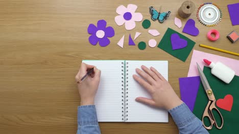 aerial footage of female writing in diary by craft equipment