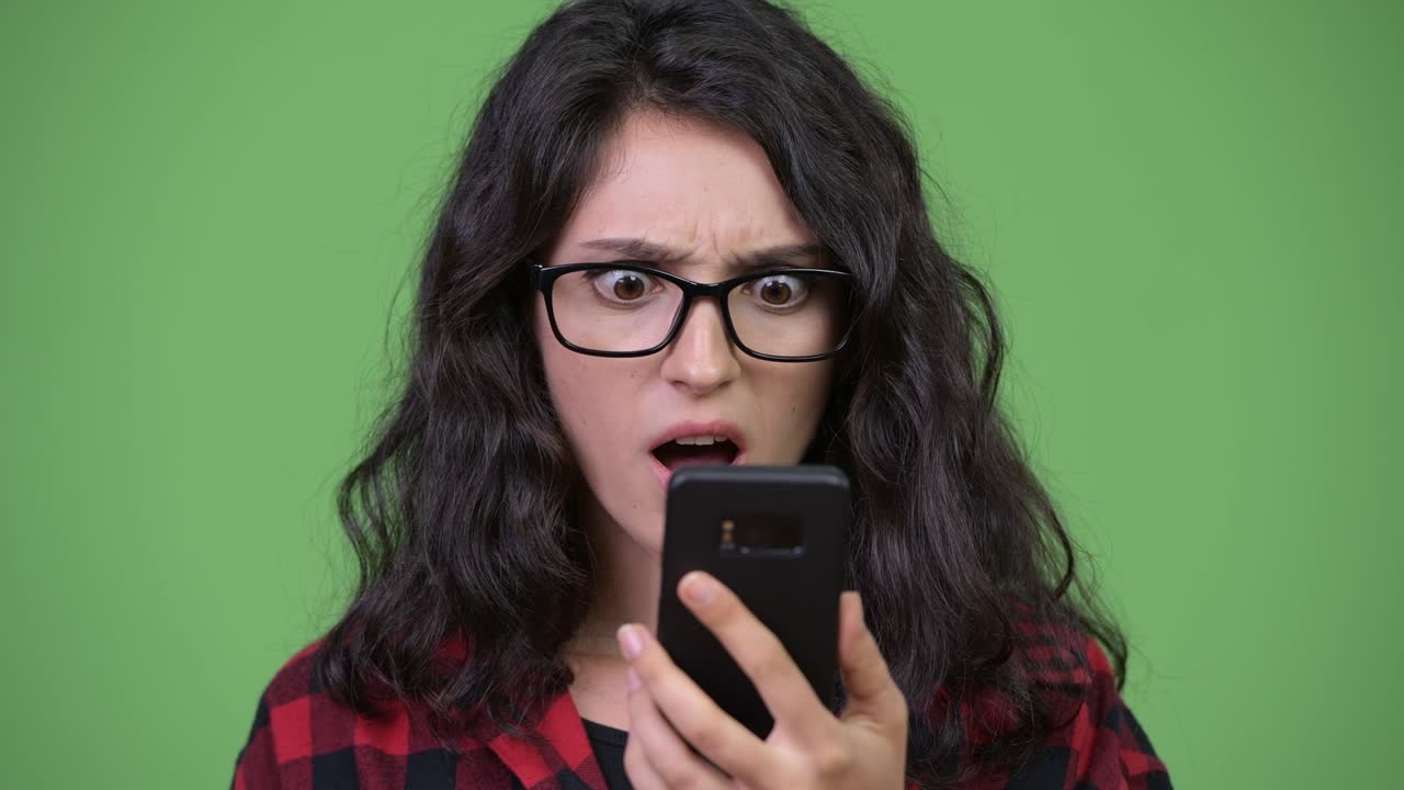 Young beautiful businesswoman using phone looking shocked