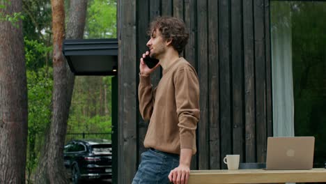 man talking on phone outside modern house