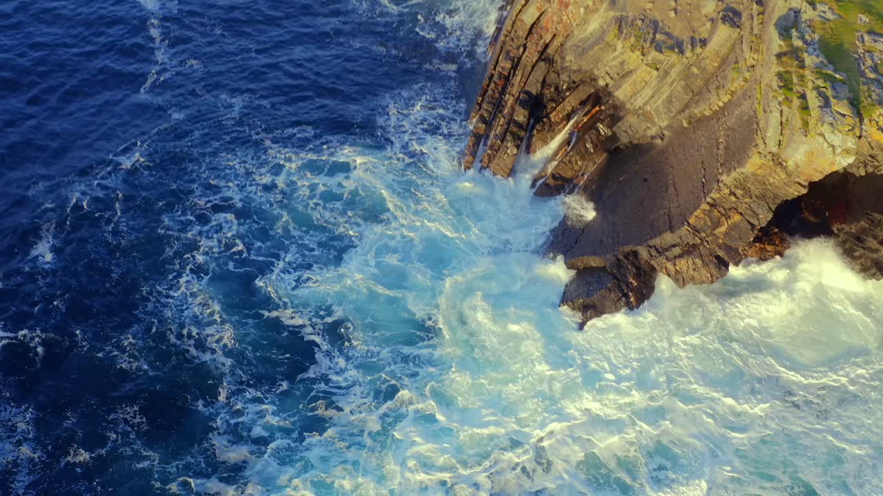 Aerial View of Dramatic Ocean Waves Crashing Against Rocky Cliffs