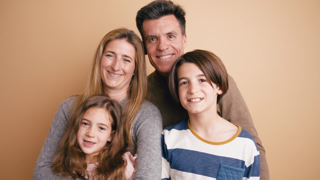 Glad familie på fire poserer og smiler i studie