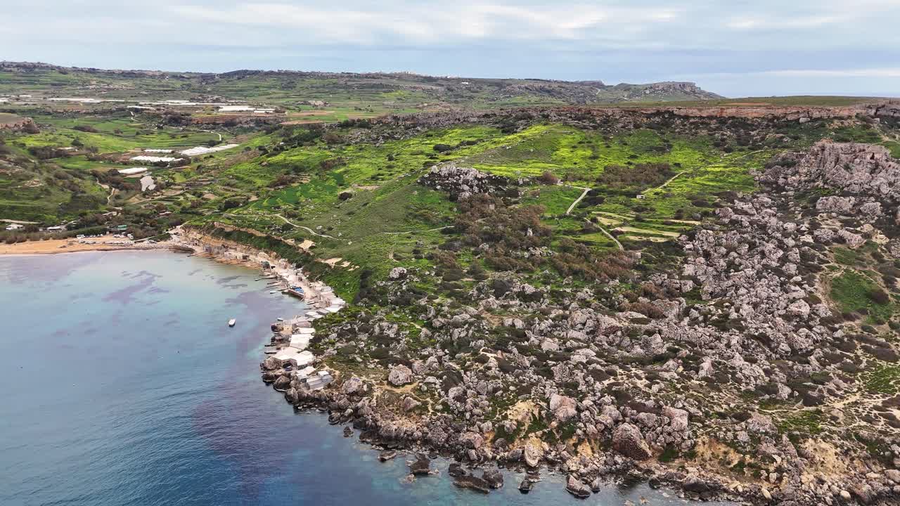 Baia di Qarraba, Mellieħa, Malta, con costa rocciosa formata da calcare a globigerine e pendii argillosi con vegetazione del bioma della gariga mediterranea che si affaccia su una baia riparata lungo il Mar Mediterraneo, panoramica