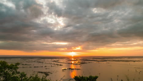 Goldene-Sonnenuntergangsreflexion-über-Dem-Horizont-Des-Zurückweichenden-Fruchtbaren-Wassers-Des-Tonle-Sap-Sees,-Das-Versunkene-Reisfelder-Am-Ende-Der-Regenzeit-Enthüllt