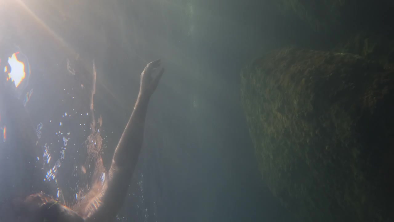 Abstract underwater view with sun rays and distorted reflections on the water surface, creating a peaceful and mysterious deep water scene