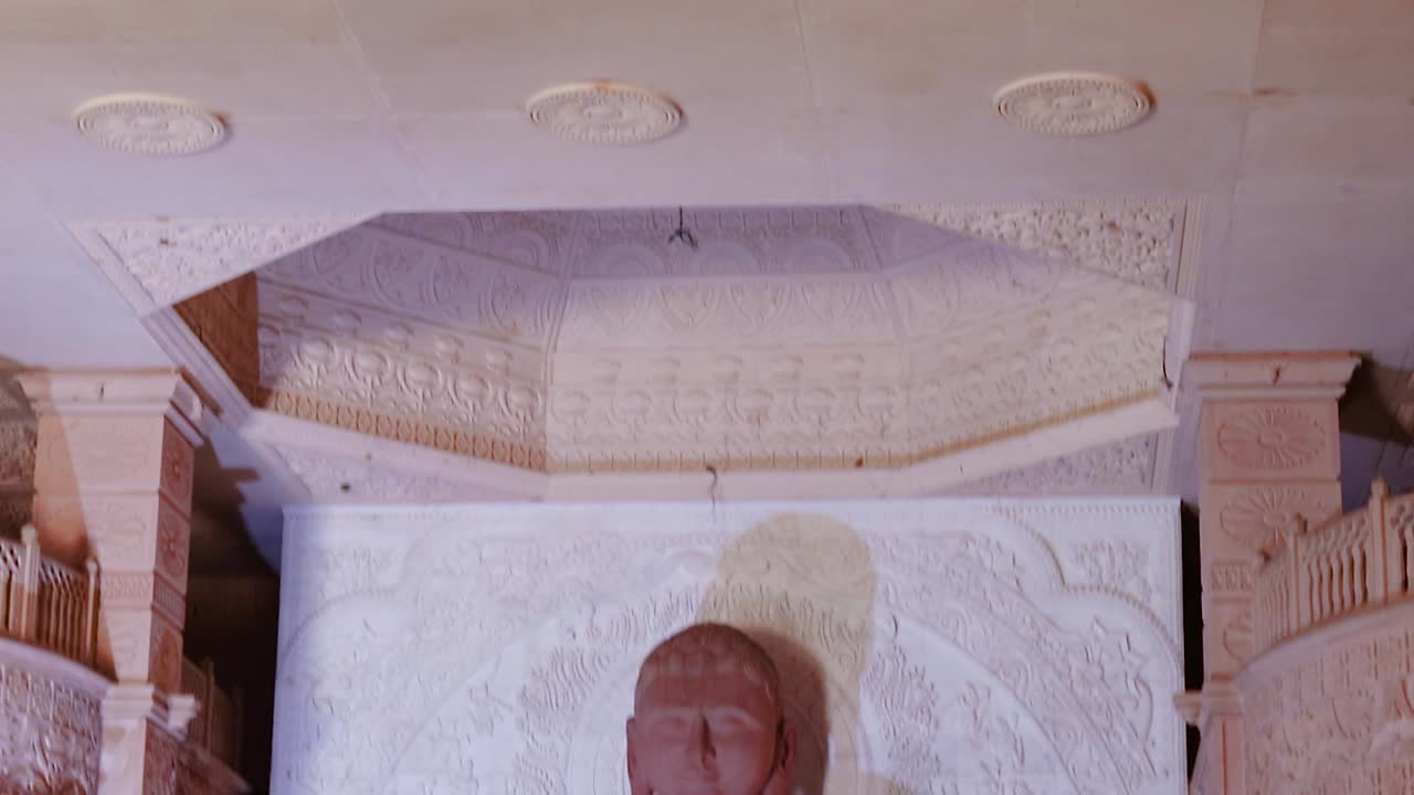 estatua sagrada de piedra roja aislada de dios jainista en meditación desde diferentes ángulos el video se tomó en shri digamber jain gyanoday tirth kshetra, nareli jain mandir, ajmer, rajasthan, india