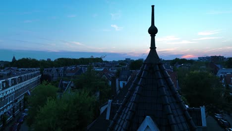 Cinematic-shot-floating-over-a-city-balcony-revealing-a-small-town-skyline-during-sunset