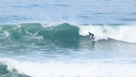 surfer making a single bottom turn on a wave in guincho surf spot