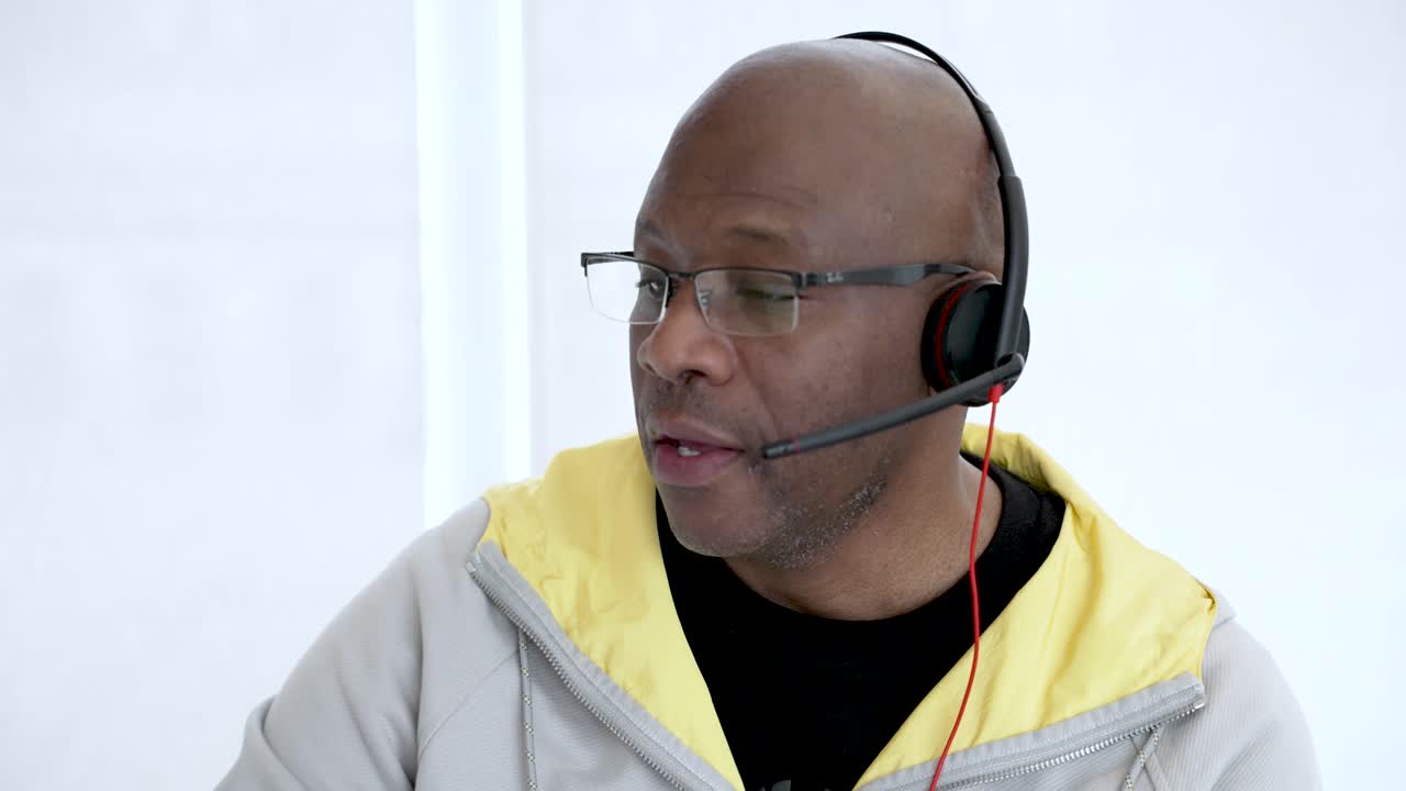 Black male customer service representative wearing headset is speaking during a conversation with a client