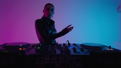 a female dj performing behind a set of turntables at a club