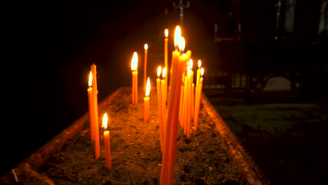 long red candles flicker a golden yellow as the camera slowly pans around them at a shallow depth of field