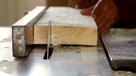 worker cutting wood board with circular saw at a furniture factory