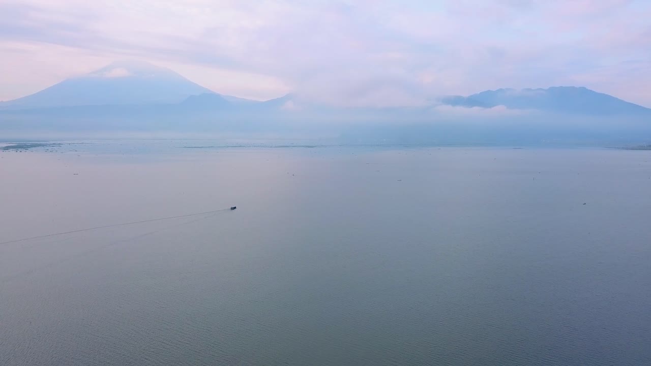 barco de pesca en la distancia cruzando lentamente el lago rawa pening en indonesia