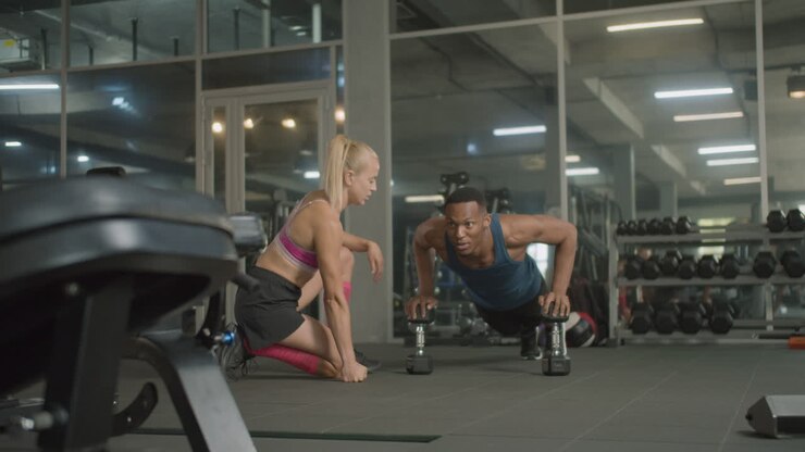 Caucasian female monitor and an athletic african american man in the gym.