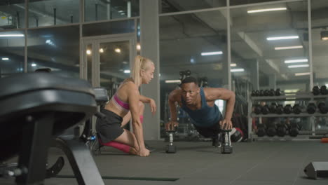 caucasian female monitor and an athletic african american man in the gym.