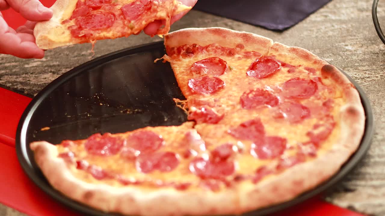 테이블 위 에 있는 페페로니 피자 의 조각 을 들어 올리는 사람